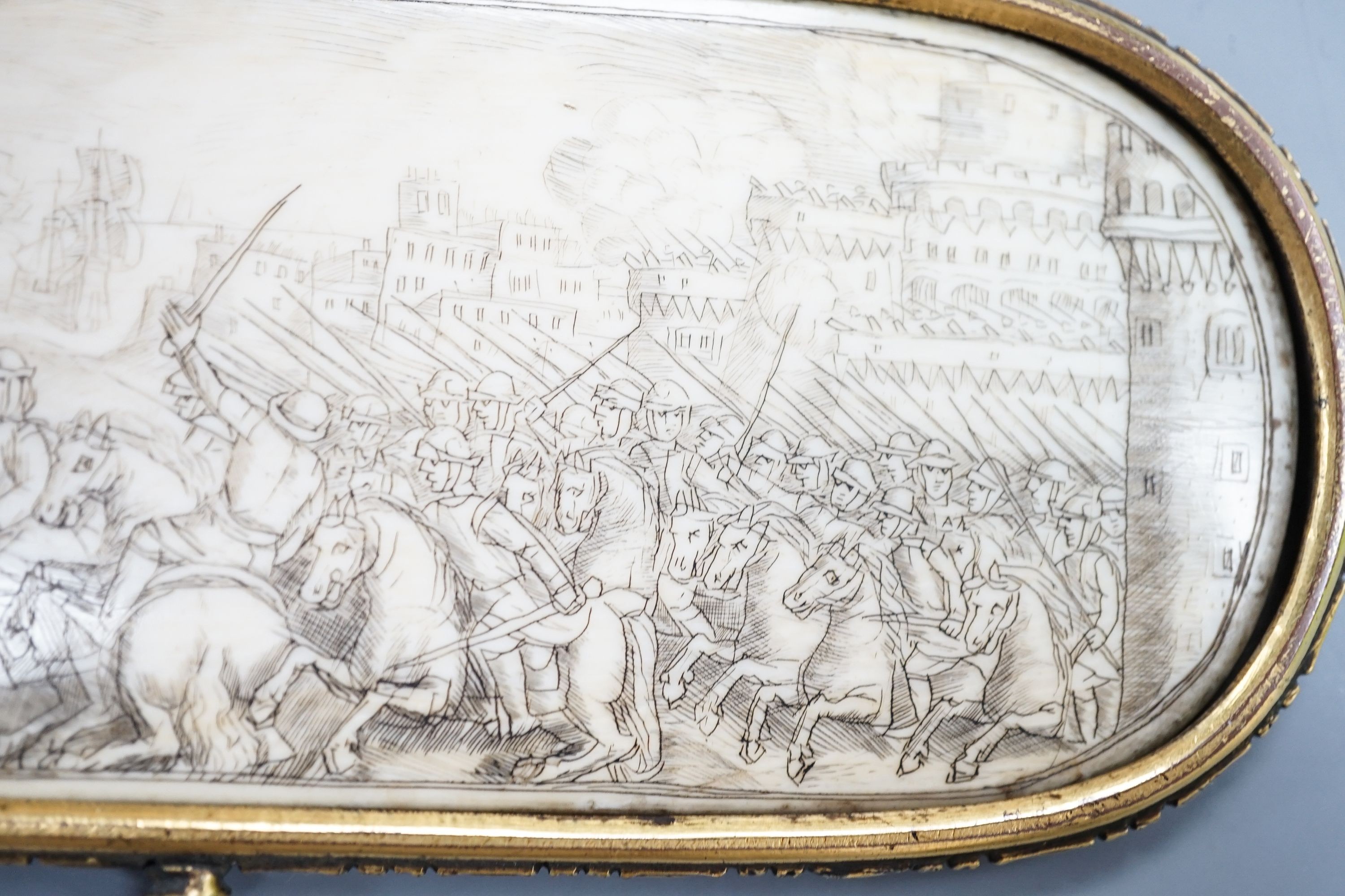 A 17th century French oval ivory plaque in a revolving metal surround, etched on both sides with battle scenes and ships in the background 17cm